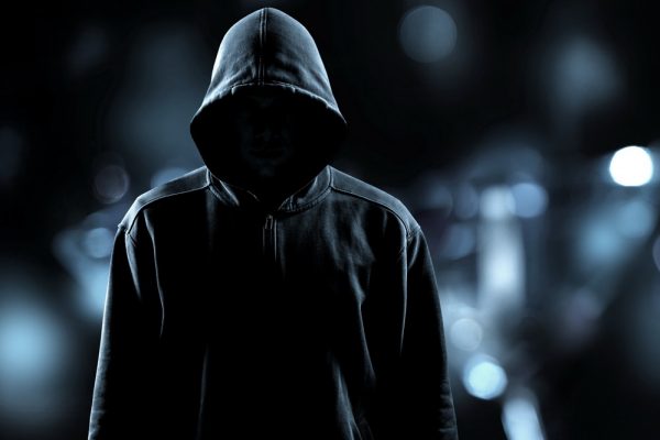 Thief in black clothes on grey background