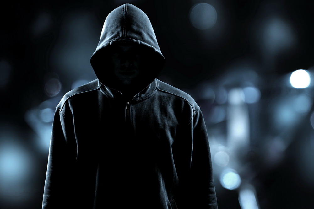 Thief in black clothes on grey background